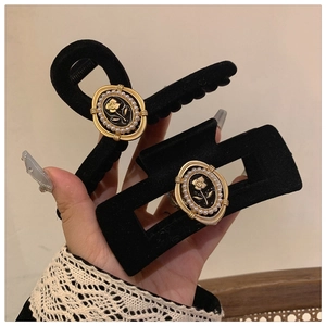 Detail of velvet black rose hair claws with vintage gold-edged oval badge and pearls