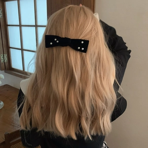 Elegant black velvet bow hair clip with white pearls on blonde wavy hair