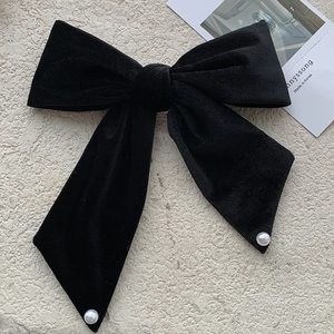 French vintage large black velvet bow hair clip with white pearl accents on stone background