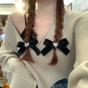 Close-up of black satin bow hair clips with silver heart charms on a female model