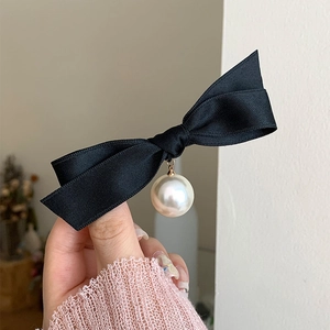 French vintage black bow hair clip with a large white pearl pendant held in hand