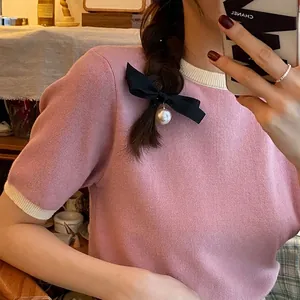 Pink knit top with contrast trim and black bow hair clip featuring pearl pendant detail