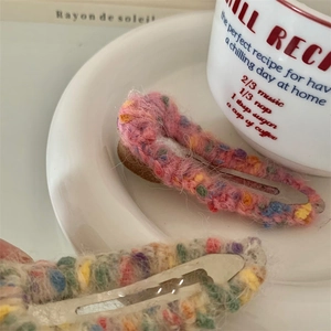 Macro shot of colorful knitted yarn duckbill hair clips with rhinestone detailing on a plate