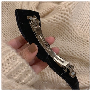 Macro shot of the sturdy silver metal spring clip and black velvet fabric of the hair bow