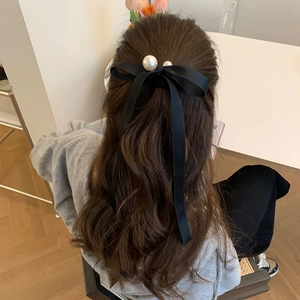 Elegant black satin bow hair clip with white pearl pendants worn on a ponytail
