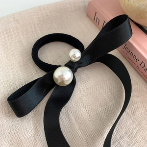Close-up of elegant black satin ribbon bow hair tie with polished faux pearl accents