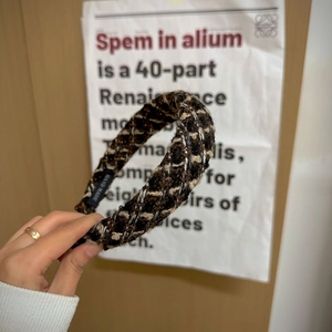 Close-up of woven tweed headband in brown and gold tones with hand made label