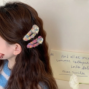 Détail de pinces à cheveux coeur avec texture tricotée et breloques en strass brillants