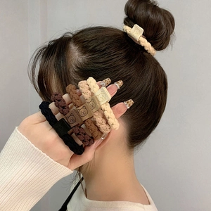 Close-up of earth-toned plush hair ties with cute bear charms in soft lighting