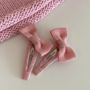 Lot de deux jolies barrettes nœuds roses avec texture sergé sur fond gris épuré
