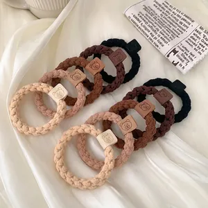Earthy tone braided elastic hair ties set with leather bear charms on silk fabric