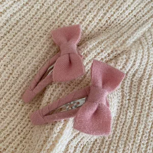 Vue détaillée de deux barrettes à nœuds roses en tissu texturé sur fond tricoté doux