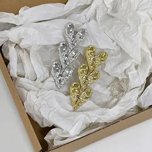Set of gold and silver heart hair clips with textured lava finish and chain ring on paper