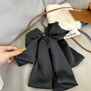 Elegant large black satin bow hair claw clip for women in a stylish handheld lifestyle shot