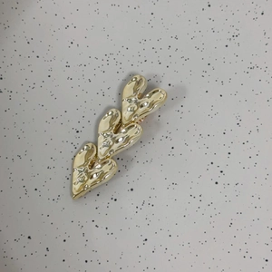 Detailed macro view of three layered golden heart hair clips with textured hammered finish