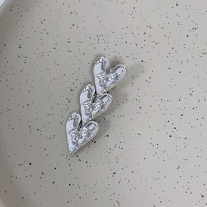 Detail view of silver heart-shaped hair clip with unique hammered metal texture and shine