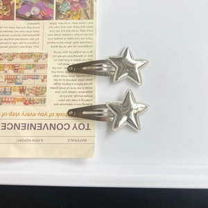 Lot de deux barrettes à cheveux argentées en forme d'étoile sur fond minimaliste