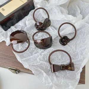 Détail de chouchous en acétate marron chocolat aux formes de nœud et de fleur