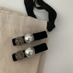 Detail of velvet hair clips featuring large pearls and grey rhinestones on fabric