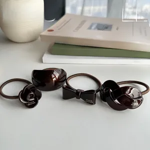 Détail de quatre élastiques à cheveux en résine marron avec camélia et nœud papillon