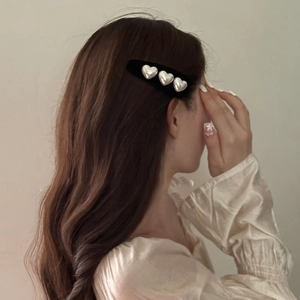 Detail of vintage velvet hair clip with three heart pearls worn on model's hair