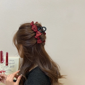 Detail of red tweed bow hair claw clip showing elegant half-up style on long hair