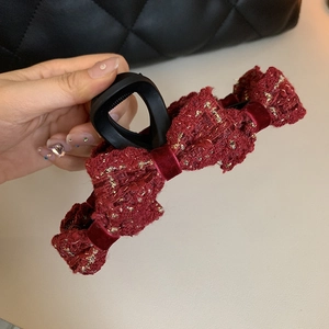 Detail showing wine red tweed bow claw clip with gold metallic threads and velvet texture