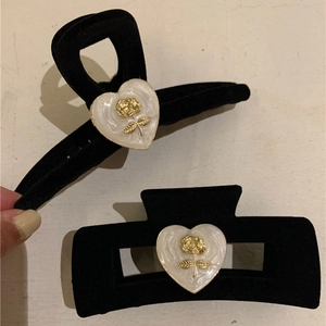 Detail of black velvet hair claws with white pearl heart and gold rose relief pattern