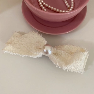 Detail of tweed bow hair clip with faux pearl embellishment and frayed edges