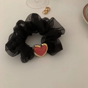 Detail von schwarzem Organza-Haargummi mit rotem Vintage-Herzanhänger und Goldrand