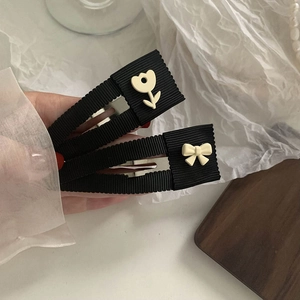 Detalle de tulipanes y lazos crema en pinzas para el cabello BB envueltas en cinta negra