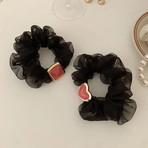 Elegante Haargummis aus schwarzem Organza mit roten Herzanhängern auf weißem Hintergrund