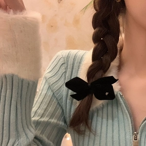 Detailed view of an elegant black velvet bow clip worn on a braided hairstyle