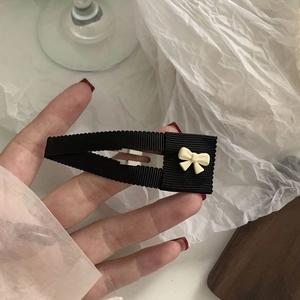 Detalle de una pinza para el cabello forrada en tela con un delicado lazo crema