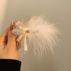 Vue détaillée d'une pince à cheveux en plumes d'autruche blanches avec nœud en satin