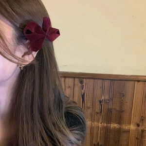 Close-up of a burgundy velvet bow hair clip on a model showing elegant side texture