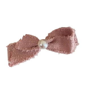 Pink tweed bow hair clip with faux pearl center and fringe detail on white background