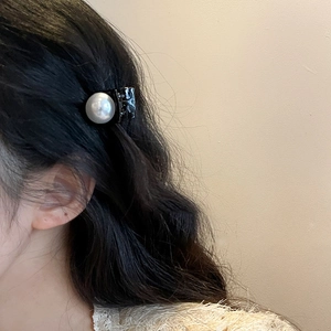 Detail view of a French vintage pearl hair clip on black resin worn as a side hair clip