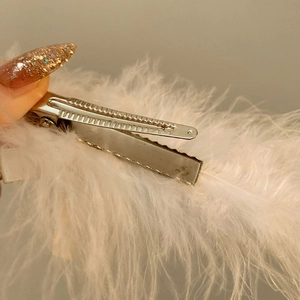 Vue détaillée de la pince à cheveux élégante en plumes d'autruche blanches et métal