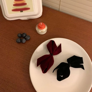 Elegant red and black velvet bow hair clips for women in a festive winter setting