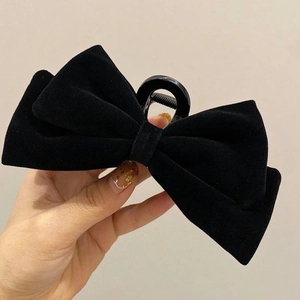 Detail of a large black velvet double-layer bow hair claw clip held in hand