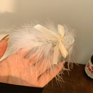 Vue détaillée d'une élégante pince à cheveux en plumes d'autruche blanches avec nœud satiné