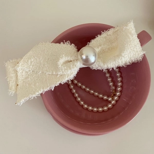 Cream tweed bow hair clip with large pearl detail in a vintage aesthetic setting