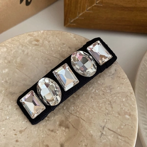 Macro detail of luxury French hair clip with five large crystal rhinestones on black base