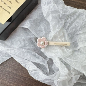 Close-up of pink flower hair clip with pearl center and Creation France gold lettering