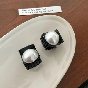 Detail of small black hair claws with large faux pearls on a ceramic tray display