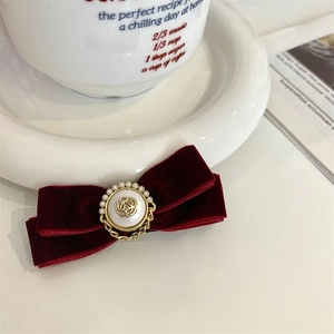 Detailopname van een vintage bordeauxrode fluwelen haarstrik met parel en gouden roos versiering