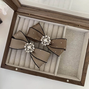 Detail of vintage camel bow hair clips with pearls and rhinestones on a wooden tray