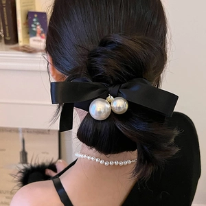 Elegant black silk bow hair scrunchie with twin pearls on a bun hairstyle
