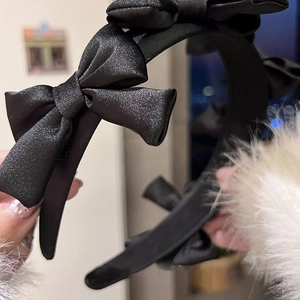Vue détaillée d'un serre-tête en satin noir orné de trois élégants nœuds papillon 3D